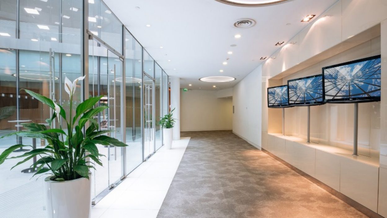 Forum Gallery with tall planters on the left hand side and three branding screens on the right hand side