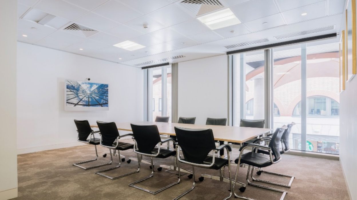 Recess 1 set boardroom table for 10 people facing a small wall ount plasma screen with a sky atrium image