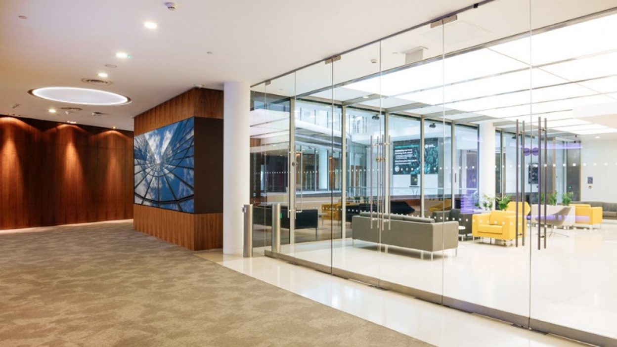 Theatre Gallery overlooking First Floor reception. Sky atrium shot on the data wall and soft furnishings in the reception in grey and yellow sofas.