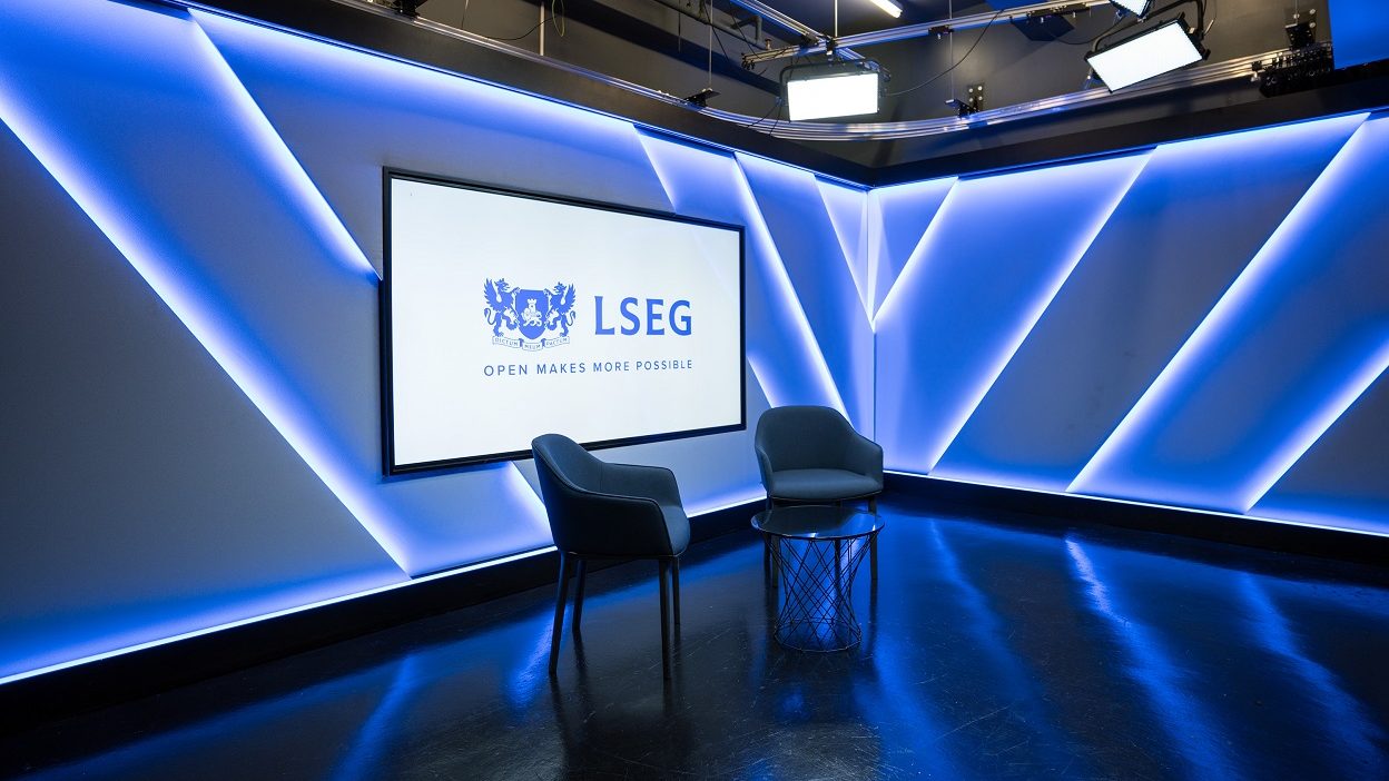 工作室的侧视图，画面中有两把椅子摆在小玻璃咖啡桌旁。后面的屏幕显示伦敦证券交易所集团 (LSEG) 徽标，说明文字为“开放创造更多可能”