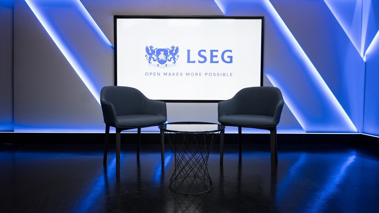 4 号工作室的广角镜头视图，画面中有两把椅子摆在小玻璃咖啡桌旁。后面的屏幕显示伦敦证券交易所集团 (LSEG) 徽标，说明文字为“开放创造更多可能”